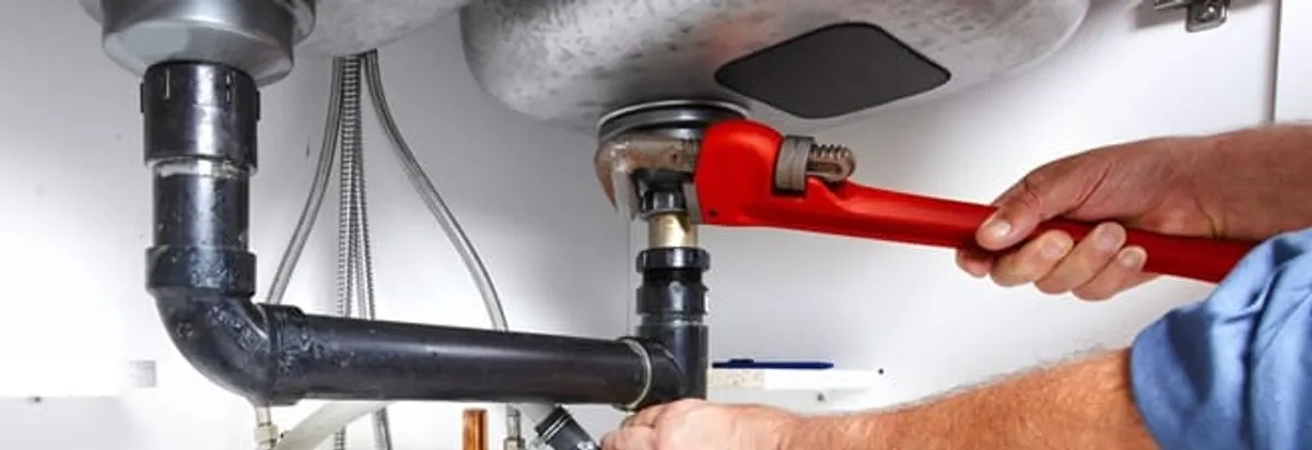 Garbage disposal repair technician tightening the sink drain and disposal connection in Riverside, CA