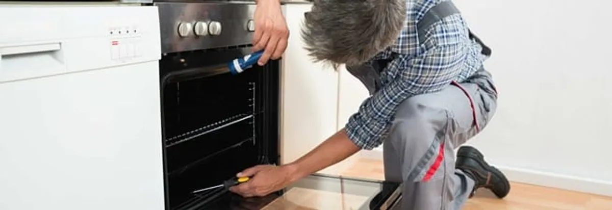 Oven repair technician inspecting and servicing an electric oven in Riverside, CA