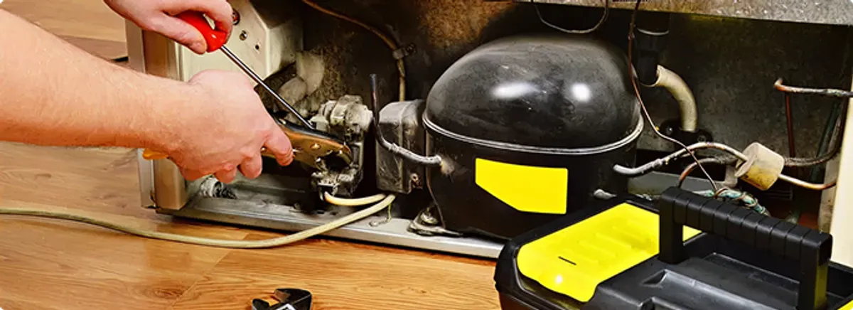 Refrigerator repair technician fixing the compressor and wiring in Riverside, CA